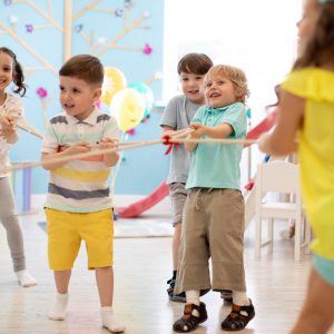 Group of kids play and pull rope together in day care. Games and physical activity for children